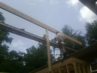Carpenter setting a ridge beam over a new addition frame — Ice Dam Removal by Roofing Brothers in Rhoadesville