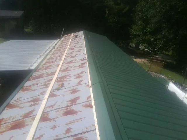 Old rusted panels beside newly installed green metal roofing — Wind Damage Roof Repair by Roofing Brothers in Rhoadesville