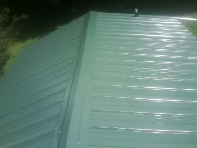 New green metal panels meeting at the ridge of a roof — Flat Roof Repair work by our crew in Rhoadesville