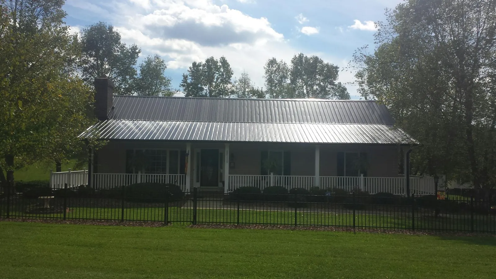 Gray metal roof on a brick ranch with a full width front porch — Gutter Guard Installation work by our crew in Rhoadesville
