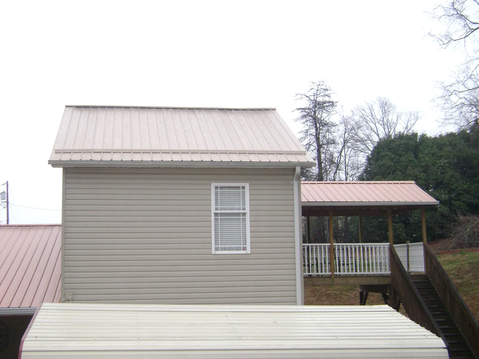 Tan metal roofs on a two story addition and attached porch, from a Roof Replacement job in Rhoadesville