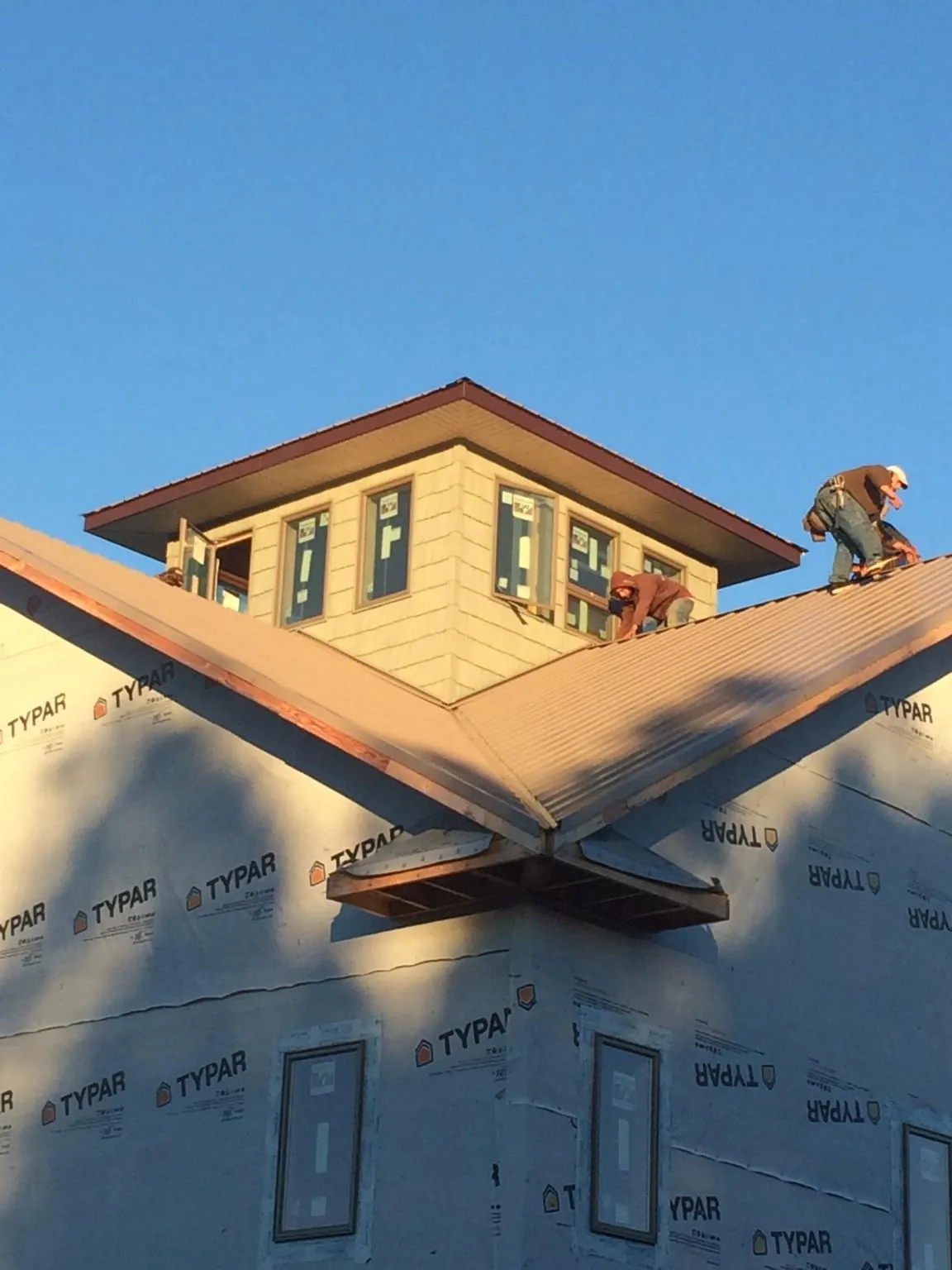 Roofers working around a rooftop cupola on a new metal roof at sunset — Roof Waterproofing in Rhoadesville by Roofing Brothers